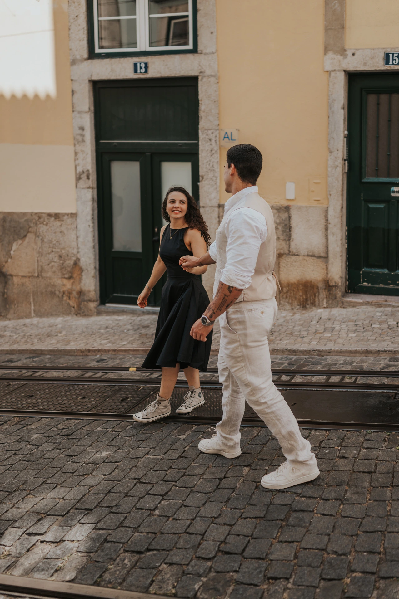The couple turning towards each other while walking beside the tiled buildings during their couple photoshoot in Lisbon.