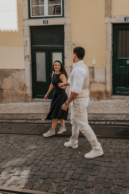 A shared glance on their street walk | Lisbon couple photoshoot The couple turning towards each other while walking beside the tiled buildings during their couple photoshoot in Lisbon.