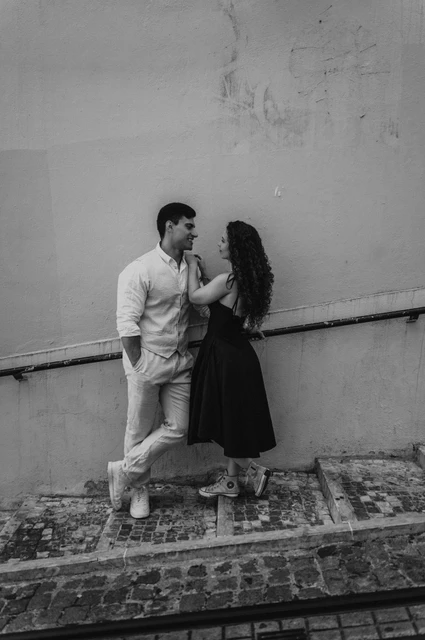An embrace beside the yellow stairway wall in black and white | Lisbon couple photoshoot Black-and-white photograph: the couple embracing on the stone stairway beside a warm yellow wall during their couple photoshoot in Lisbon.