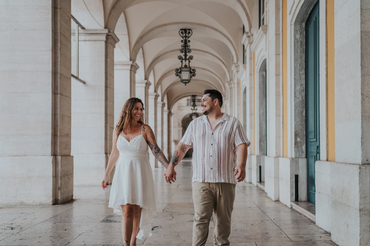 Smiles beneath the Praça do Comércio arches | Lisbon couple photoshoot The couple smiling at each other while holding hands beneath the stone arcade during their couple photoshoot in Lisbon.