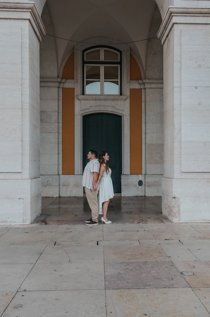 A quiet moment beneath the arch | Lisbon couple photoshoot The couple leaning close together beneath the tall arch and green doorway during their couple photoshoot in Lisbon.