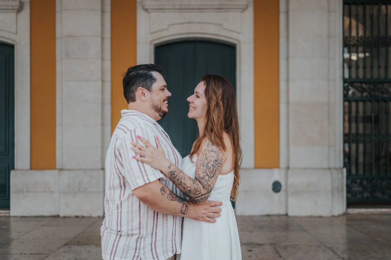 A smiling embrace beneath the arcade | Lisbon couple photoshoot A close landscape portrait of the couple smiling at each other in an embrace beneath the arcade during their couple photoshoot in Lisbon.