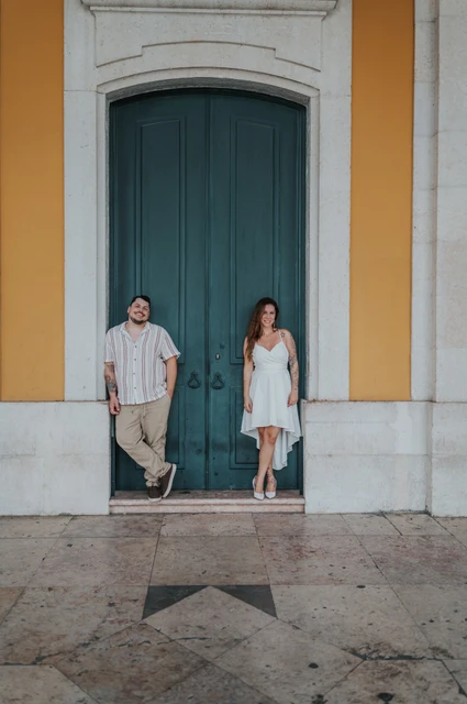 A full-length portrait at the green door | Lisbon couple photoshoot The couple standing apart beside the tall green door and yellow walls at Praça do Comércio during their couple photoshoot in Lisbon.