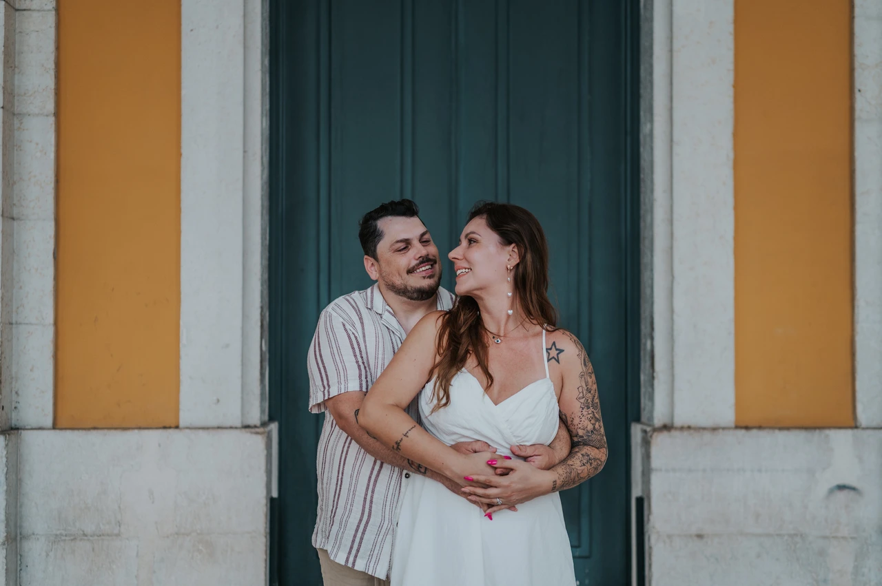A close embrace at Praça do Comércio | Lisbon couple photoshoot A close portrait of the couple smiling at each other in an embrace by the green door during their couple photoshoot in Lisbon.