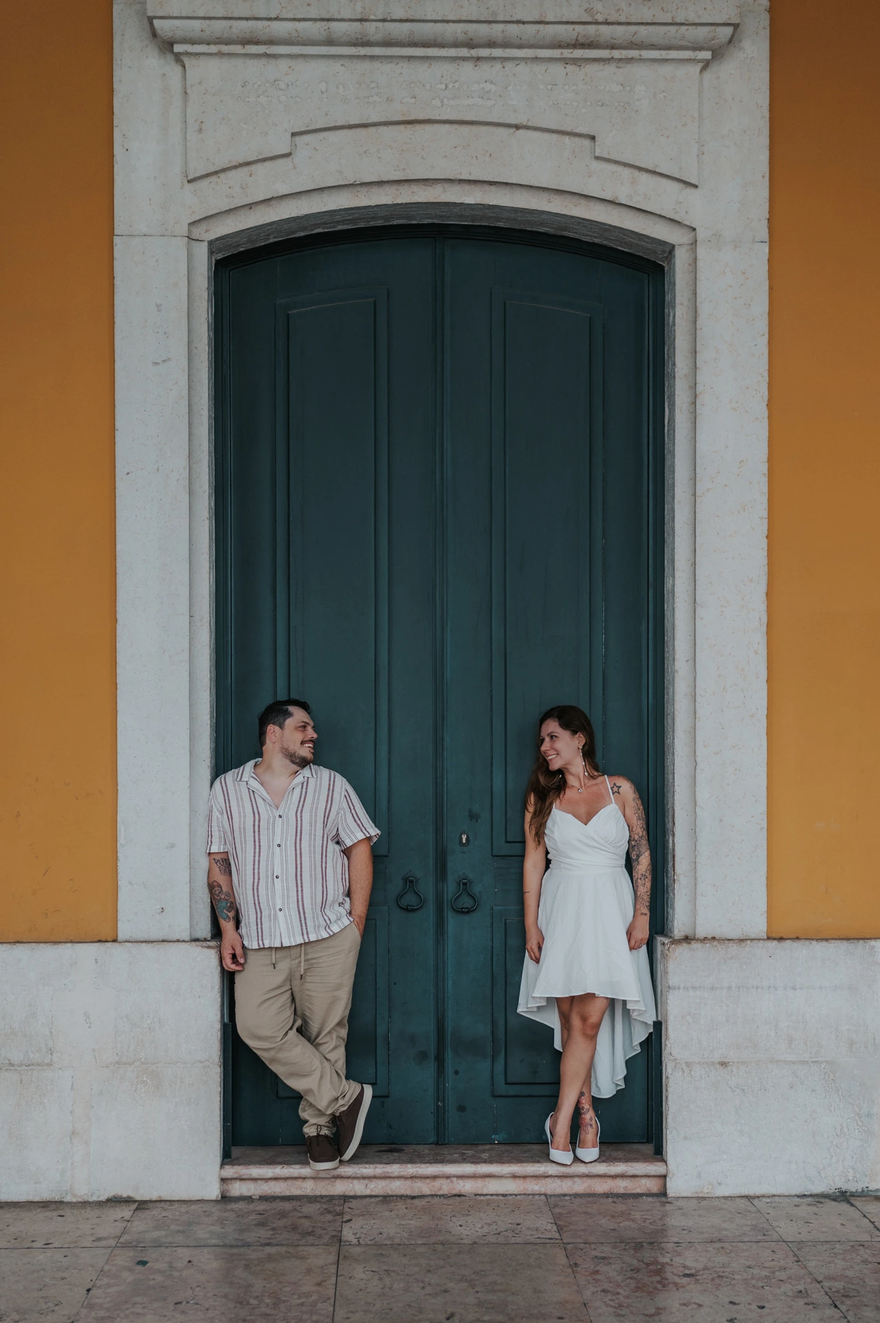 A closer full-length portrait of the couple leaning on either side of the green door during their couple photoshoot in Lisbon.
