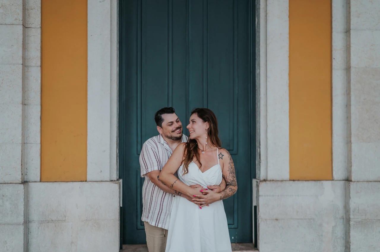 An embrace beside the green door | Lisbon couple photoshoot The man embracing his partner from behind in front of the green door during their couple photoshoot in Lisbon.