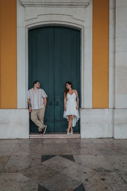 A shared glance across the doorway | Lisbon couple photoshoot The couple looking across at one another beside the tall green door during their couple photoshoot in Lisbon.