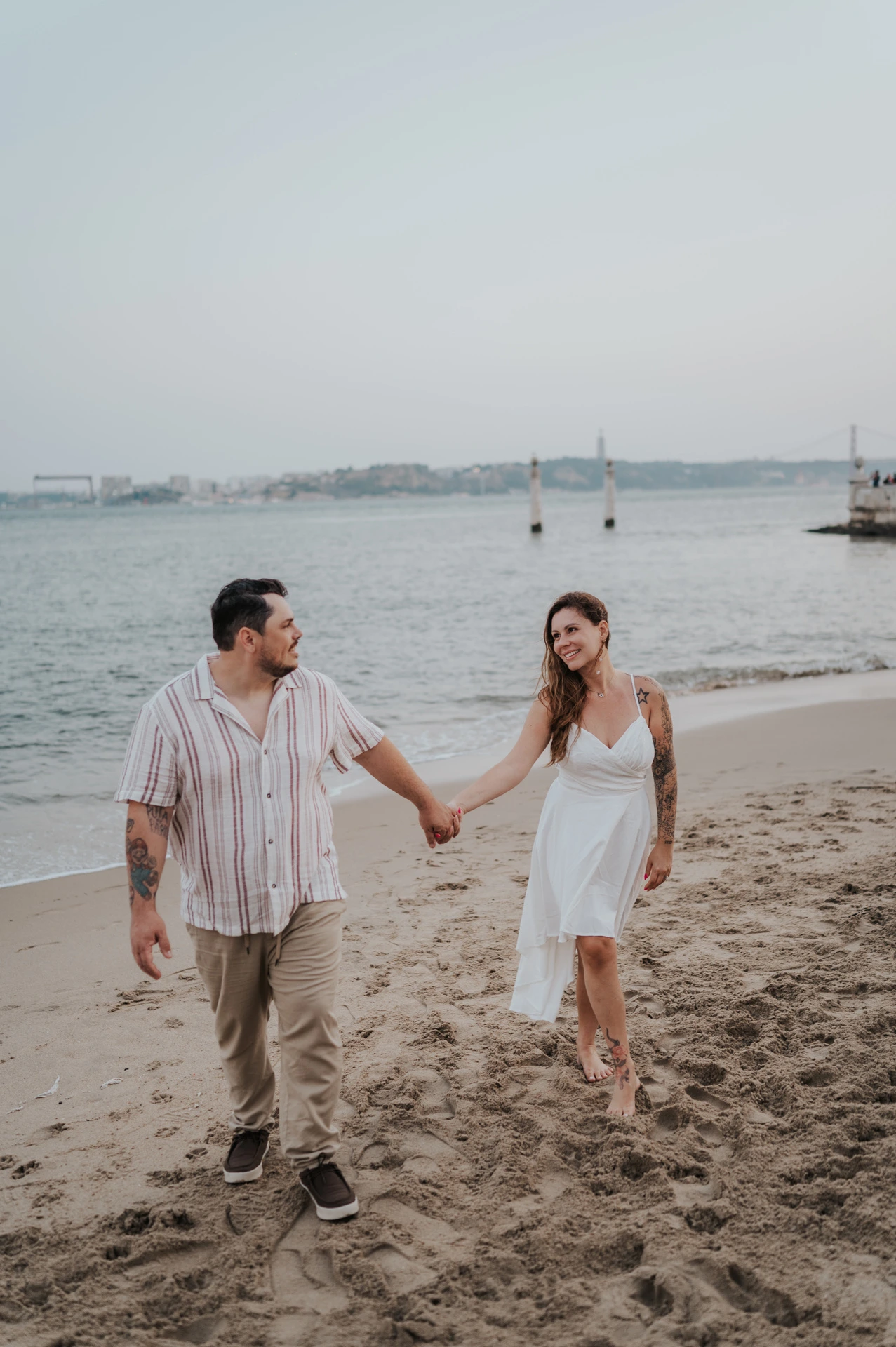 A closer portrait of the couple holding hands while walking beside the river during their couple photoshoot in Lisbon.