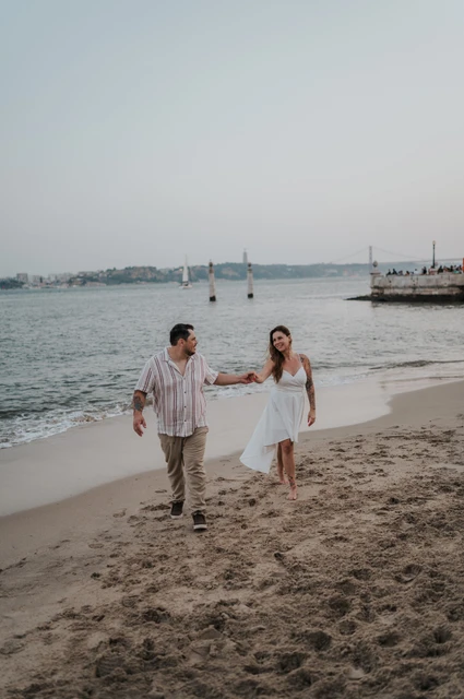 A walk along the river beach | Lisbon couple photoshoot The couple walking hand in hand along the little beach beside the river during their couple photoshoot in Lisbon.