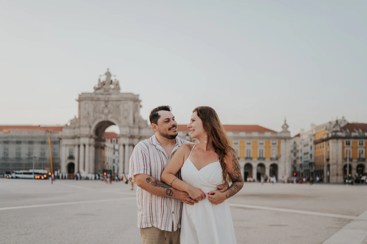 An embrace with the arch behind them | Lisbon couple photoshoot The couple embracing in the square with the monumental arch behind them during their couple photoshoot in Lisbon.