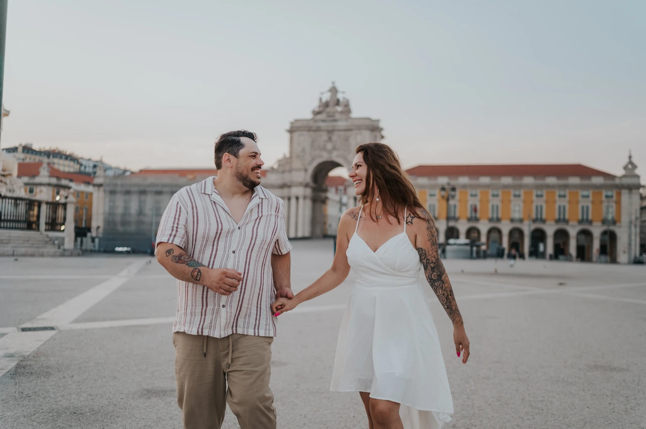 Joined hands against the yellow facades | Lisbon couple photoshoot A wide portrait of the couple walking hand in hand with the yellow square behind them during their couple photoshoot in Lisbon.