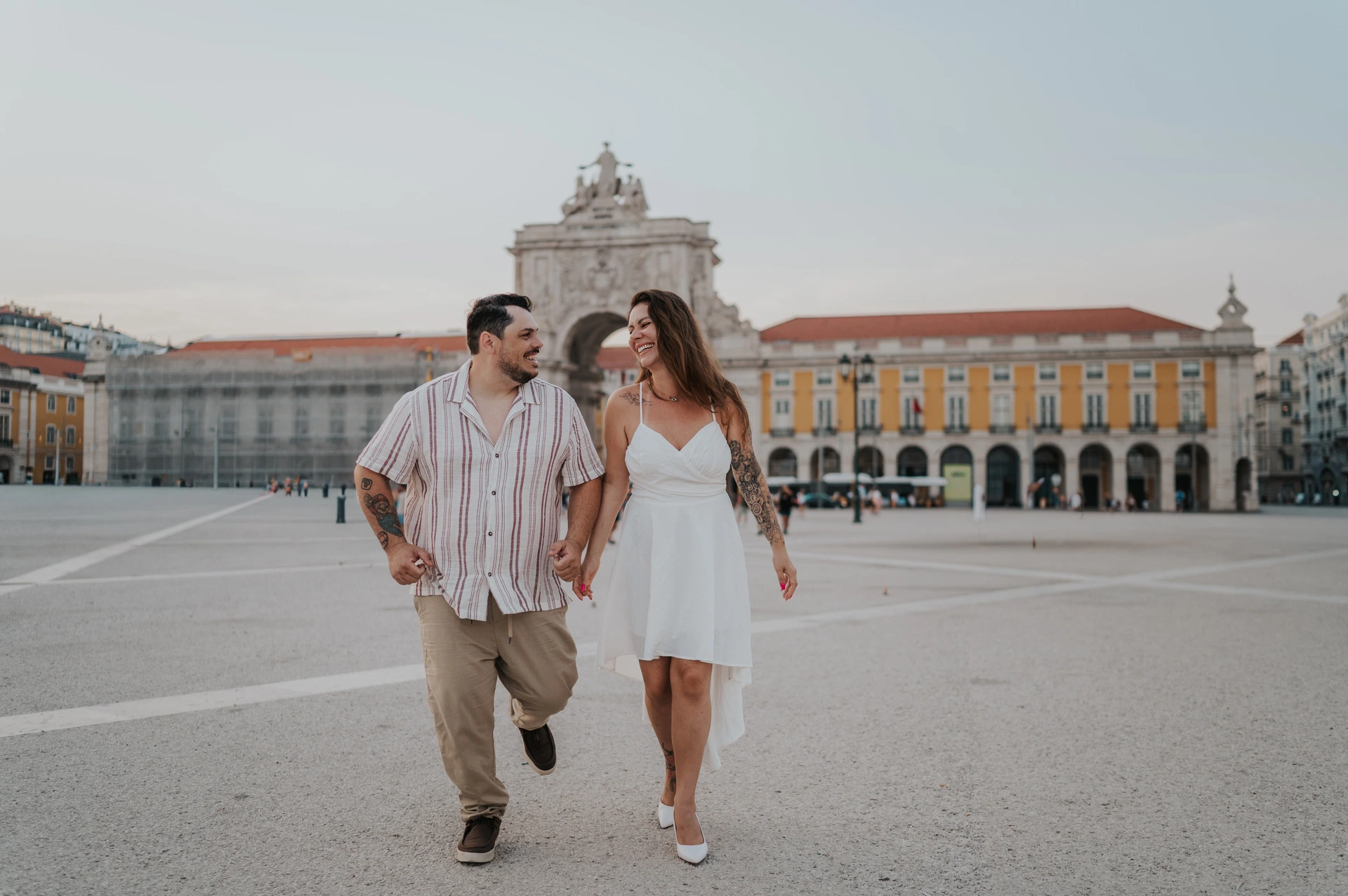 The couple taking lively steps together across Praça do Comércio during their couple photoshoot in Lisbon.