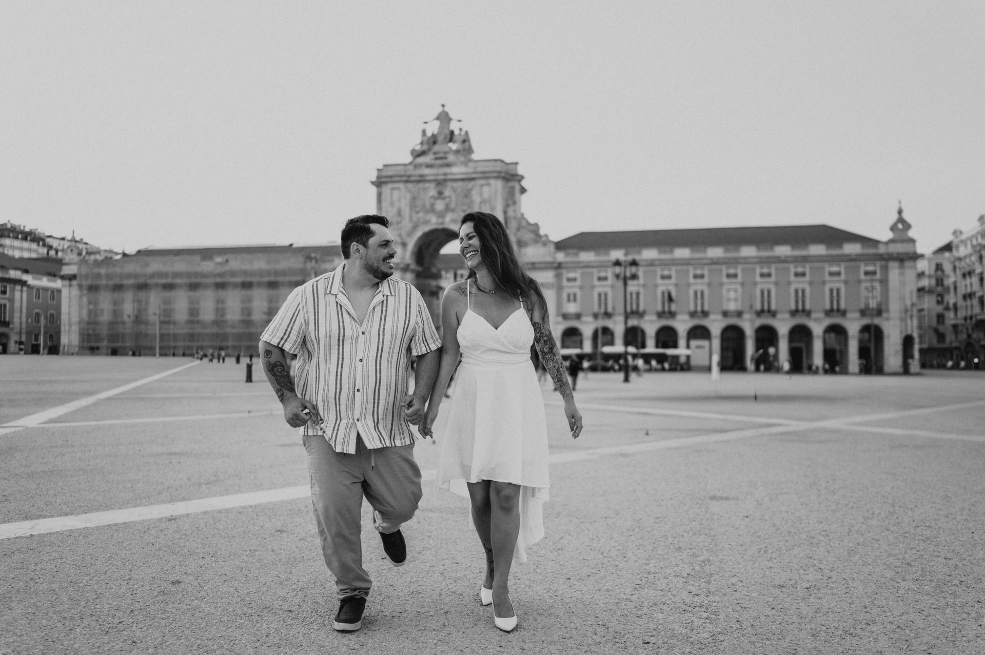 A black-and-white photograph of the couple moving together across the square during their couple photoshoot in Lisbon.