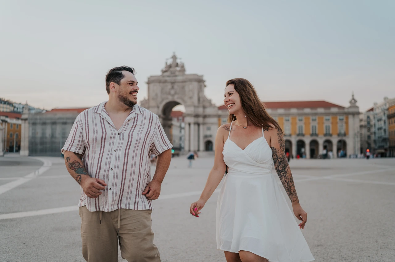 A smile together in the square | Lisbon couple photoshoot The couple smiling at each other as they walk across Praça do Comércio during their couple photoshoot in Lisbon.