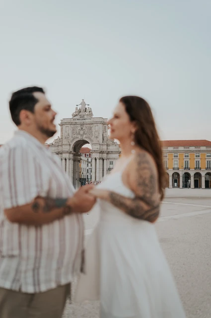 A soft portrait against the square’s arch | Lisbon couple photoshoot A softly focused portrait of the couple holding hands with the square’s arch sharp behind them during their couple photoshoot in Lisbon.