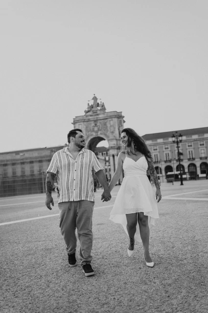 A square walk in black and white | Lisbon couple photoshoot A black-and-white photograph of the couple walking across Praça do Comércio during their couple photoshoot in Lisbon.
