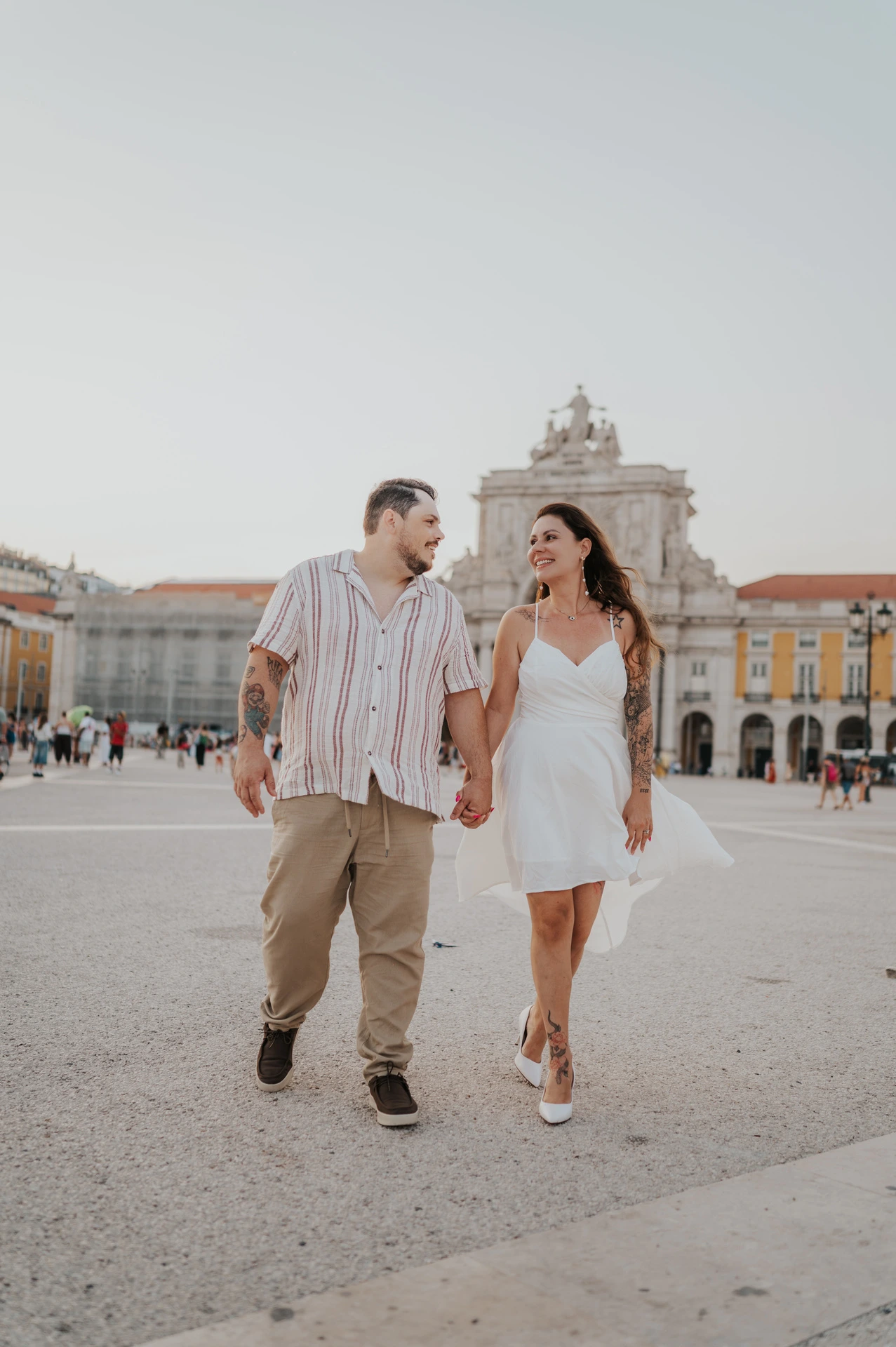 The couple sharing a glance as they walk across Praça do Comércio during their couple photoshoot in Lisbon.