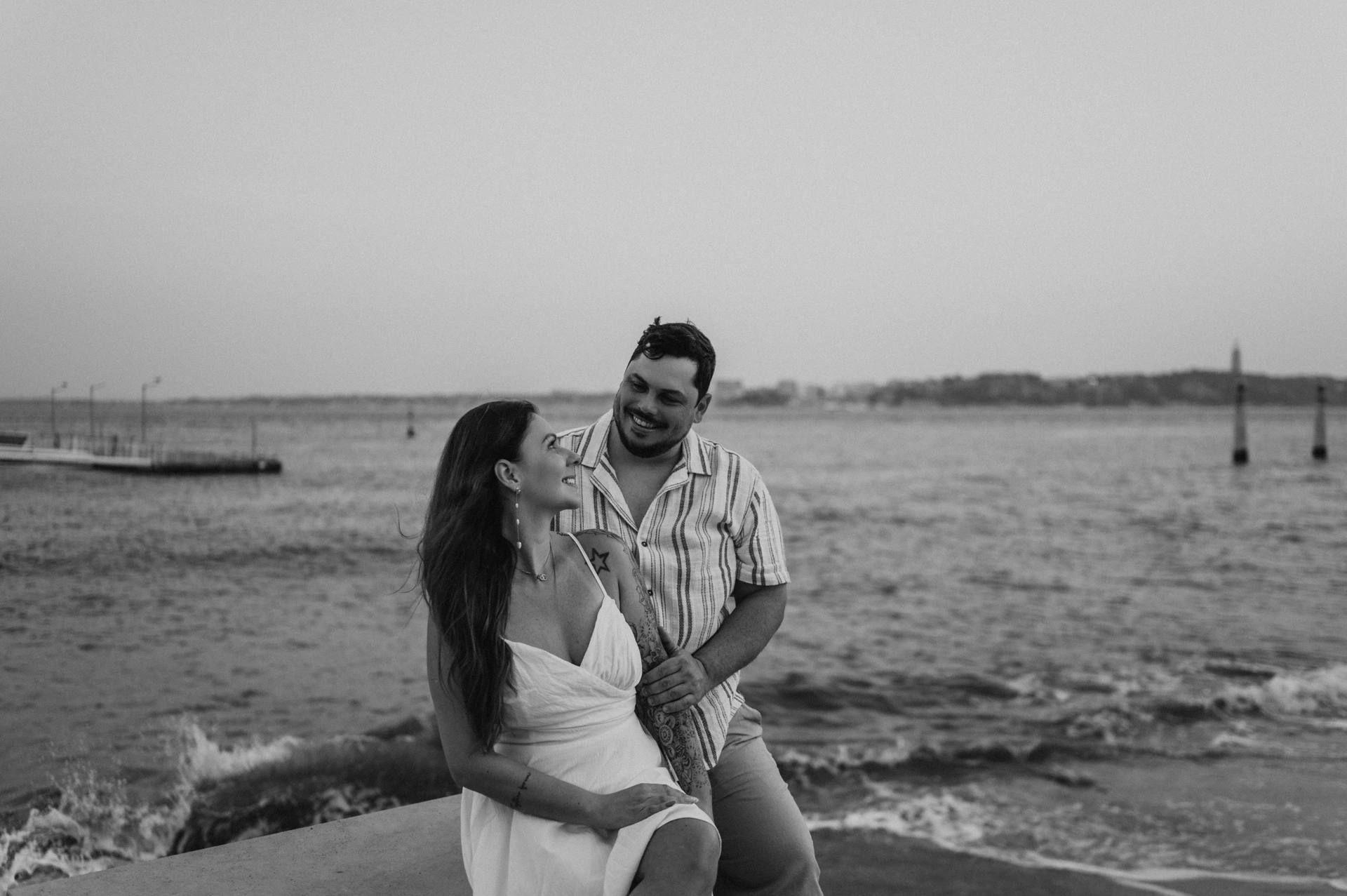 A black-and-white portrait of the couple together beside the waterfront wall during their couple photoshoot in Lisbon.