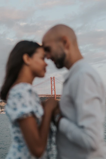 Foreheads together in soft focus | Lisbon couple photoshoot The couple leaning their foreheads together in a softly focused waterfront portrait during their couple photoshoot in Lisbon.