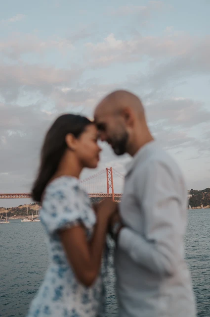 A soft embrace beside the water | Lisbon couple photoshoot A softly focused vertical portrait of the couple leaning close together by the river during their couple photoshoot in Lisbon.