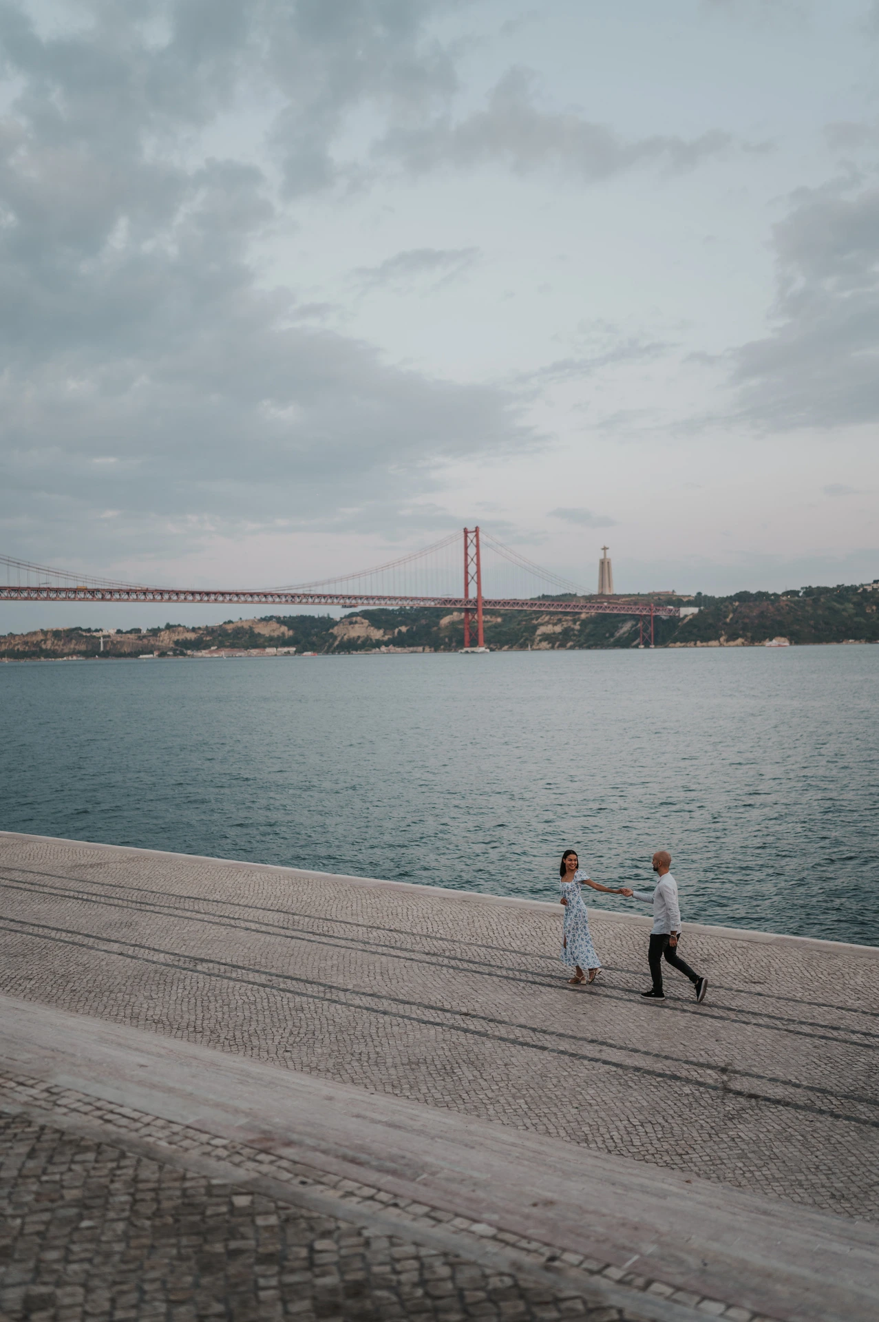 The couple turning towards each other on the waterfront, photographed from above during their couple photoshoot in Lisbon.