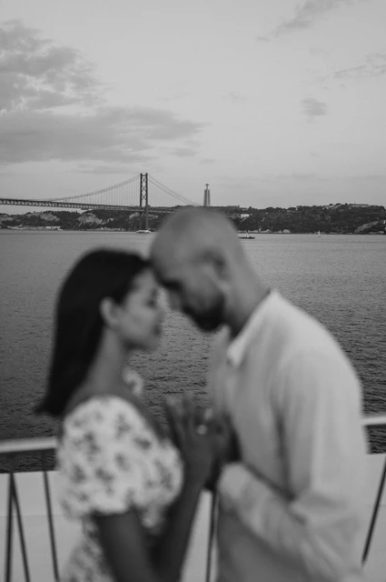 A soft railing portrait in black and white | Lisbon couple photoshoot A softly focused black-and-white portrait of the couple leaning together at the river railing during their couple photoshoot in Lisbon.