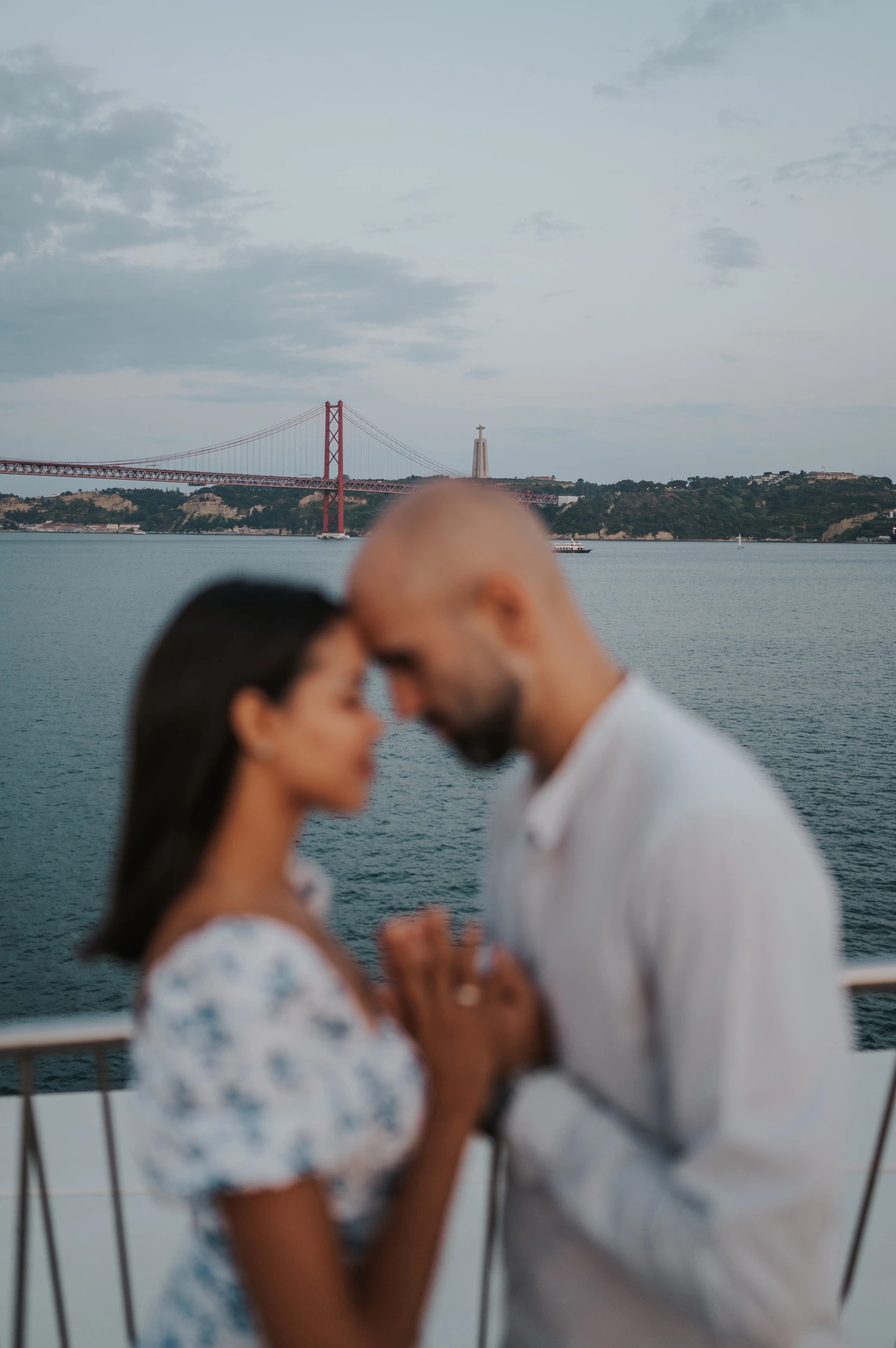A softly focused portrait of the couple leaning their foreheads together beside the river railing during their couple photoshoot in Lisbon.