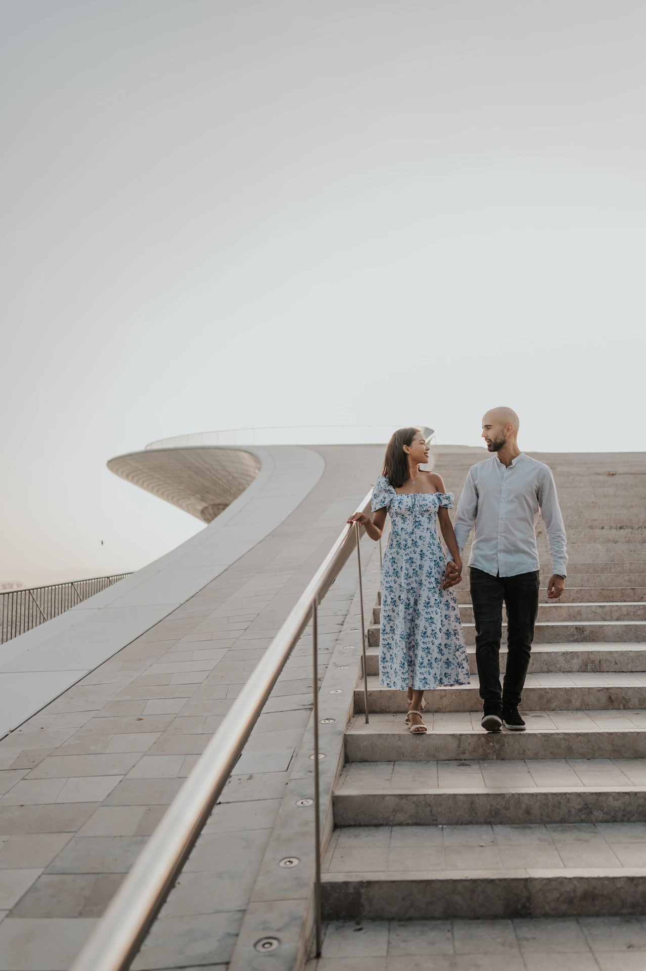 The couple walking down the MAAT staircase hand in hand during their couple photoshoot in Lisbon.