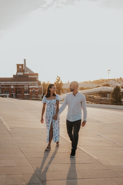 The couple looking at each other as they walk across the MAAT plaza during their couple photoshoot in Lisbon.