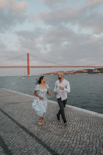 A playful walk along the waterfront | Lisbon couple photoshoot The couple taking lively steps together along the cobbled waterfront during their couple photoshoot in Lisbon.