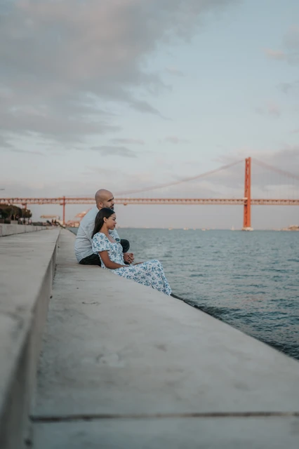A side portrait beside the water | Lisbon couple photoshoot A side view of the couple seated close together on the waterfront steps during their couple photoshoot in Lisbon.
