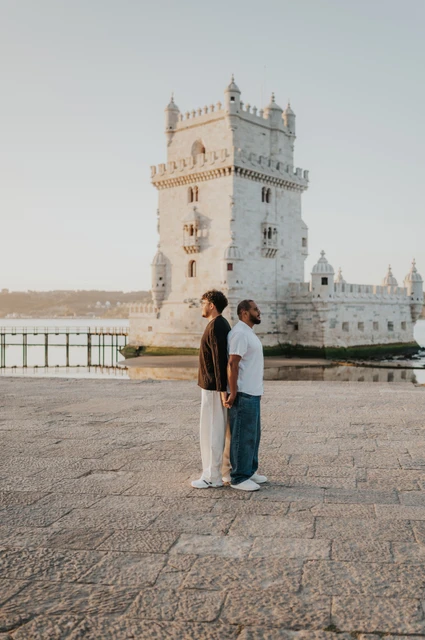 Back to back beside Belém Tower | Lisbon couple photoshoot The couple standing back to back in front of Belém Tower during their couple photoshoot in Lisbon.