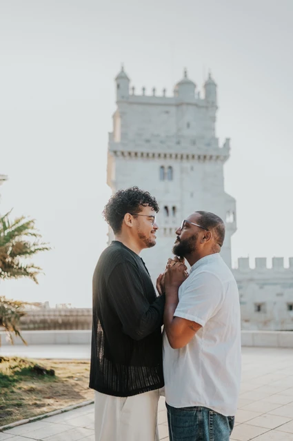 A close moment beside the tower | Lisbon couple photoshoot A close portrait of the couple leaning towards each other with Belém Tower behind them during their couple photoshoot in Lisbon.