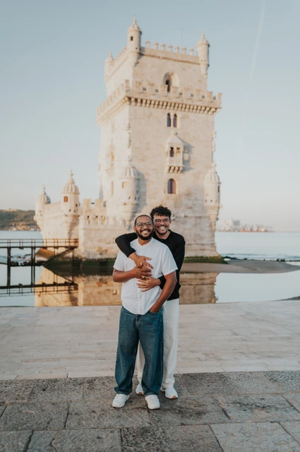 A full-length tower embrace | Lisbon couple photoshoot A full-length portrait of the couple embracing in front of Belém Tower during their couple photoshoot in Lisbon.