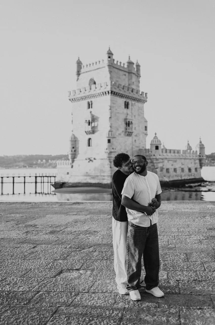 A waterfront embrace in black and white | Lisbon couple photoshoot A black-and-white photograph of the couple standing in an embrace beside Belém Tower during their couple photoshoot in Lisbon.