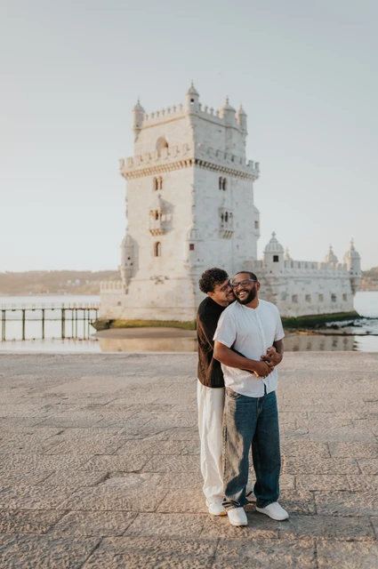 Close together in front of the tower | Lisbon couple photoshoot A full-length portrait of the couple holding each other in front of Belém Tower during their couple photoshoot in Lisbon.