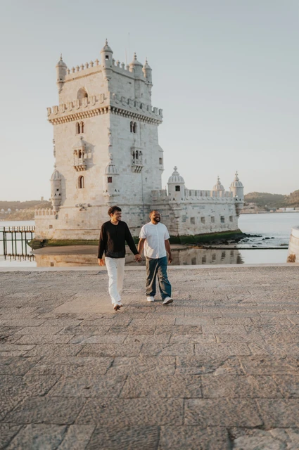 A shared glance on the paving | Lisbon couple photoshoot The couple looking at each other as they walk beside Belém Tower during their couple photoshoot in Lisbon.