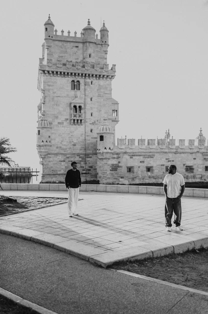 A wide tower portrait in black and white | Lisbon couple photoshoot A black-and-white portrait of the couple standing apart on the paving in front of Belém Tower during their couple photoshoot in Lisbon.