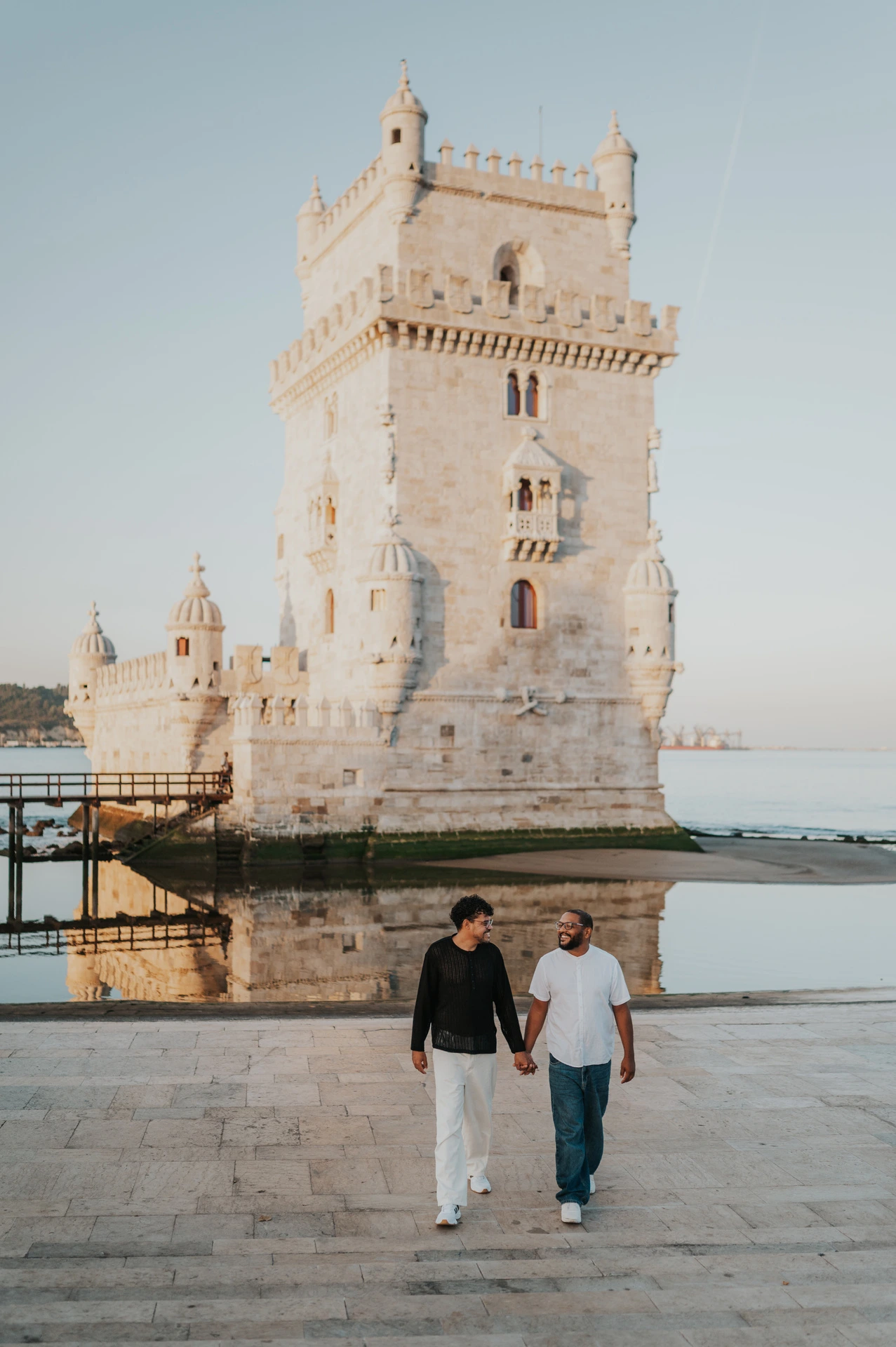 The couple looking towards each other as they walk across the paving at Belém Tower during their couple photoshoot in Lisbon.