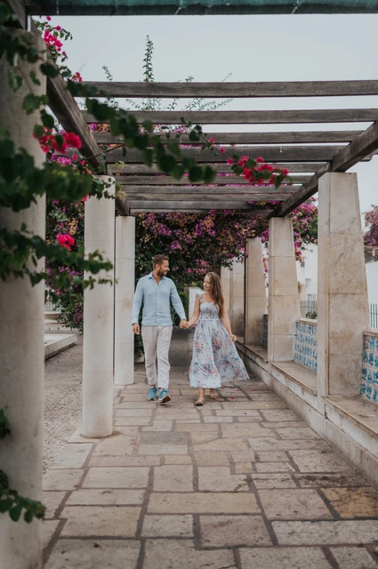A shared glance beneath the pergola | Lisbon couple photoshoot The couple looking at each other as they walk beneath the pergola at Santa Luzia during their couple photoshoot in Lisbon.