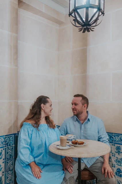Coffee together at Pastéis de Belém | Lisbon engagement photoshoot The couple smiling at one another over coffee and pastries at a small tiled café table during their engagement photoshoot in Lisbon.