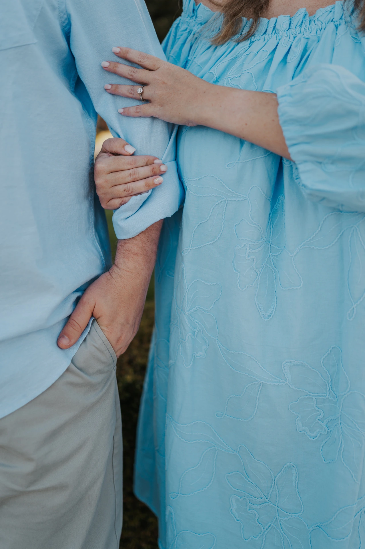 A close detail of the woman’s engagement ring and the couple’s blue outfits during their engagement photoshoot in Lisbon.
