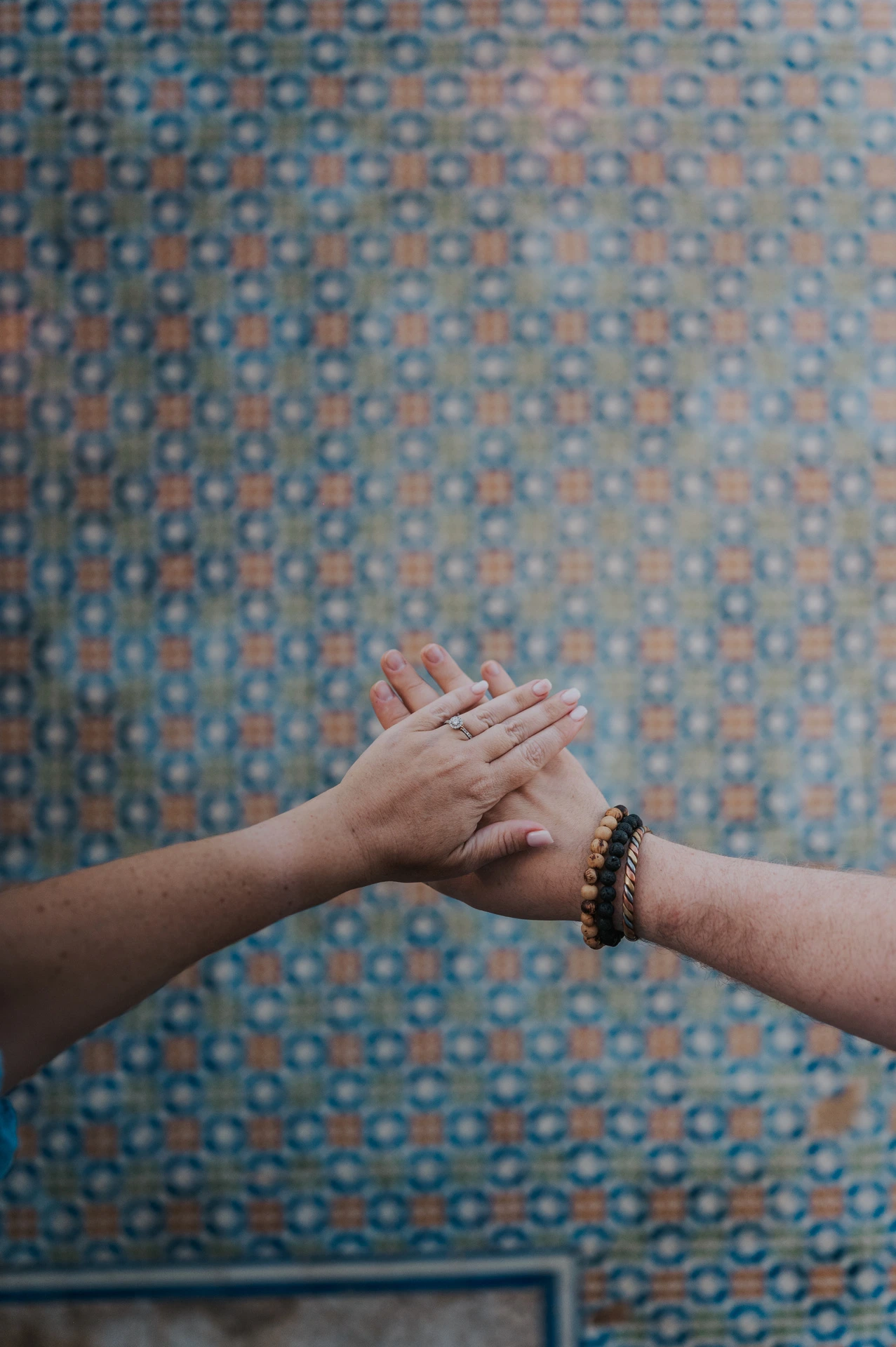 A close detail of the couple’s joined hands against the patterned tile wall during their engagement photoshoot in Lisbon.