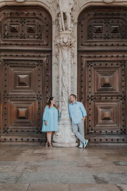 A portrait between the monastery doors | Lisbon engagement photoshoot The couple leaning on either side of a carved stone column between the monastery’s wooden doors during their engagement photoshoot in Lisbon.
