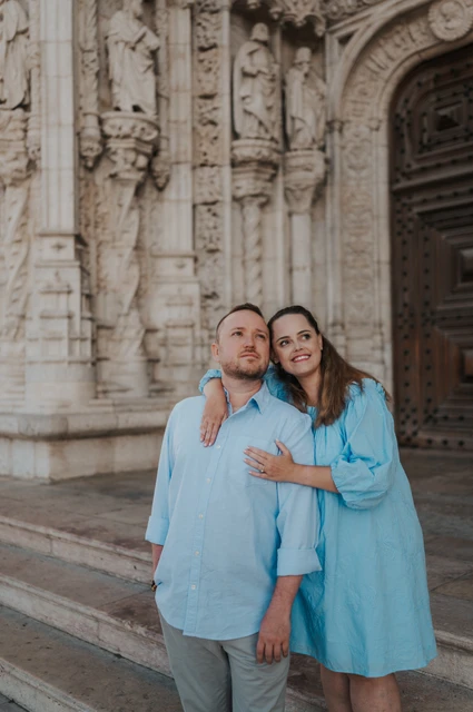 An embrace outside Jerónimos Monastery | Lisbon engagement photoshoot The woman with an arm around her partner’s shoulder as they smile outside the monastery during their engagement photoshoot in Lisbon.