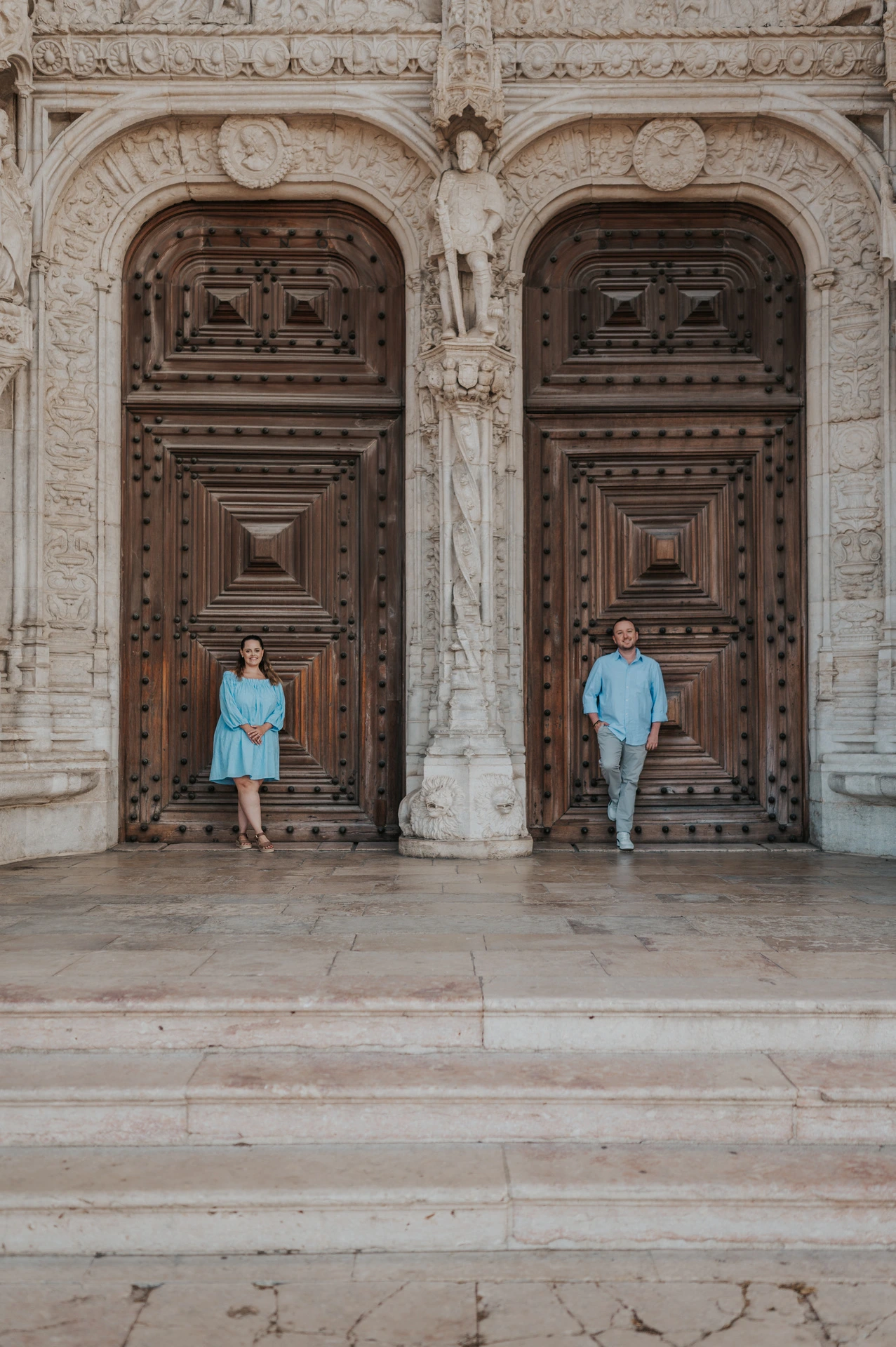 The couple standing apart against the monastery’s large wooden doors during their engagement photoshoot in Lisbon.