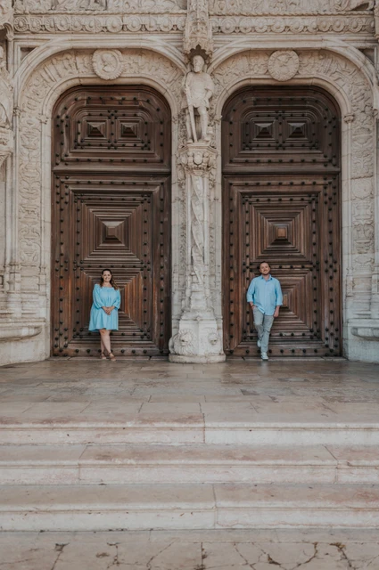 A wide portrait against the monastery doors | Lisbon engagement photoshoot The couple standing apart against the monastery’s large wooden doors during their engagement photoshoot in Lisbon.