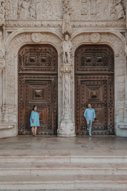 A wide portrait against the monastery doors | Lisbon engagement photoshoot The couple standing apart against the monastery’s large wooden doors during their engagement photoshoot in Lisbon.