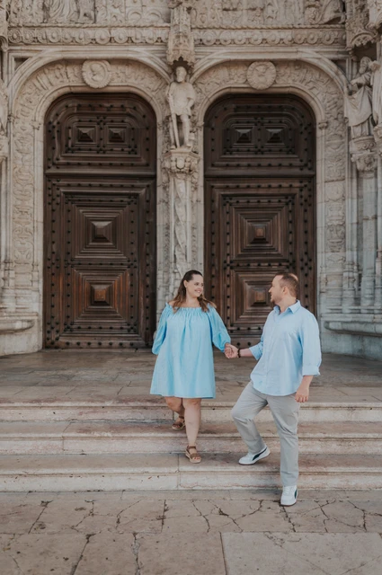 Hand in hand on the monastery steps | Lisbon engagement photoshoot The couple holding hands and moving together on the steps outside Jerónimos Monastery during their engagement photoshoot in Lisbon.