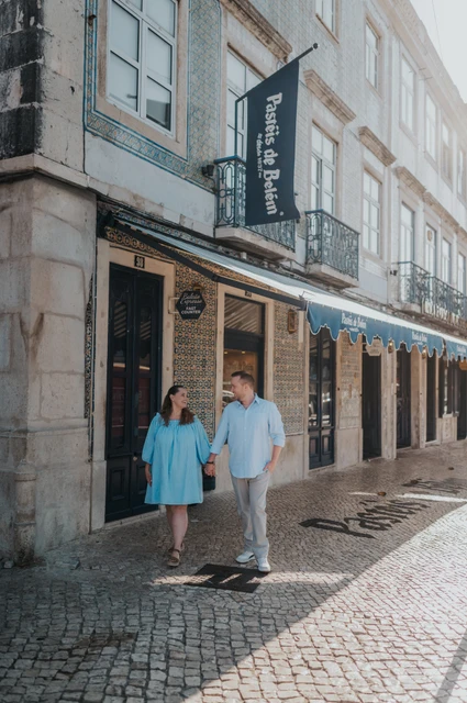 The couple walking hand in hand outside Pastéis de Belém during their engagement photoshoot in Lisbon.